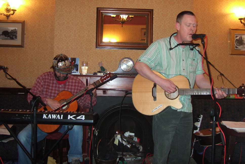 Nottingham singer song writer Cookie playing guitar and singing with Alan Robinson playing Banjo in the background at the Travellers Rest Draycott